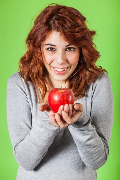 Menina adolescente segurando uma maçã vermelha em fundo verde — Fotografia de Stock