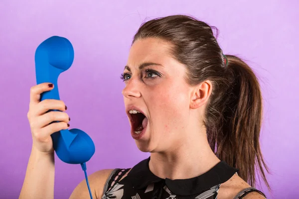 Jovem mulher gritando contra receptor — Fotografia de Stock