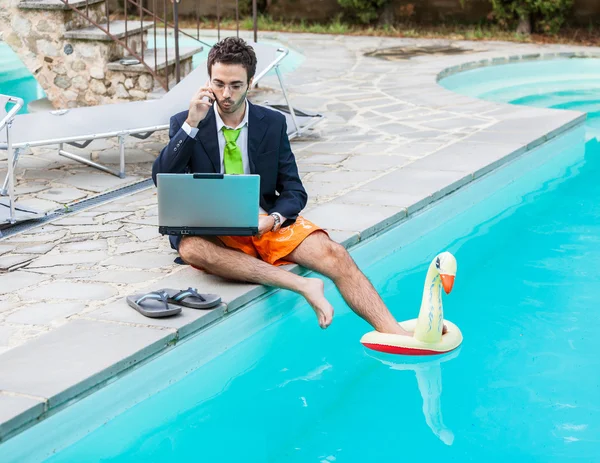 Grappige jonge zakenman met zwembroek naast het zwembad — Stockfoto