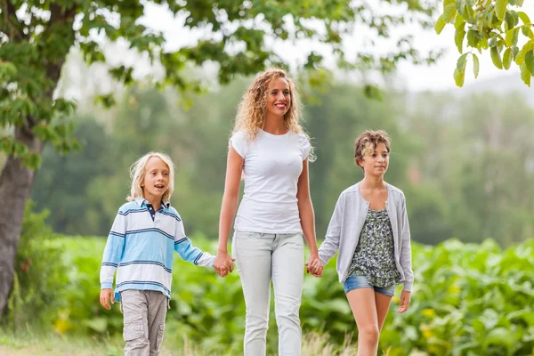 Krásná mladá žena s dvěma dětmi mimo — Stock fotografie