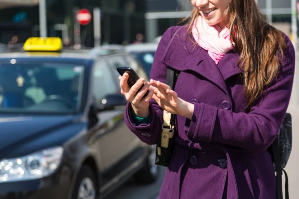 Ung kvinna talar på mobila väntar på taxi — Stockfoto