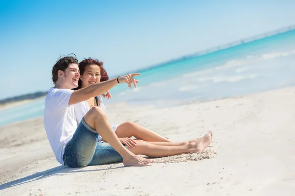 Молодая пара, сидящая на Карибском пляже — стоковое фото