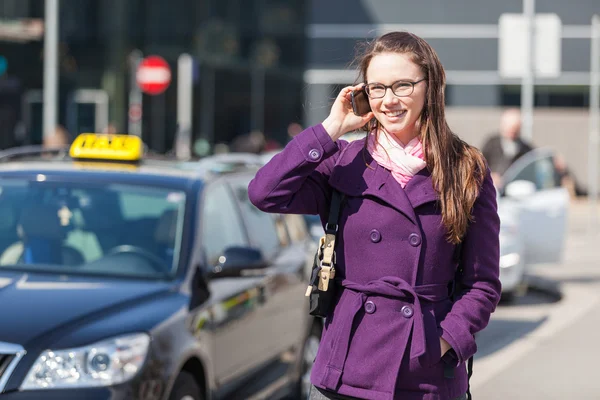 Mladá žena mluví o mobilních čekání taxi — Stock fotografie