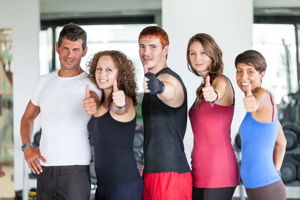 Grupo de en el gimnasio con pulgares hacia arriba — Foto de Stock