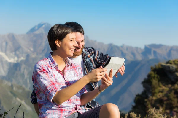 Pár s digitálním tabletu na vrcholu hory — Stock fotografie