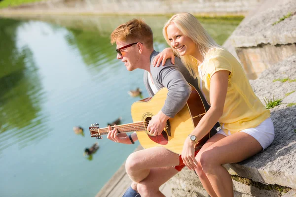 Młoda para z gitara w parku — Zdjęcie stockowe