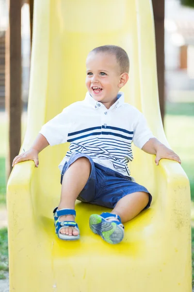 Мальчик играет на слайде в парке — стоковое фото