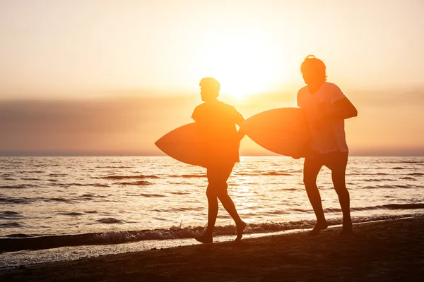 Zwei Jungen mit Surfbrettern bei Sonnenuntergang — Stockfoto