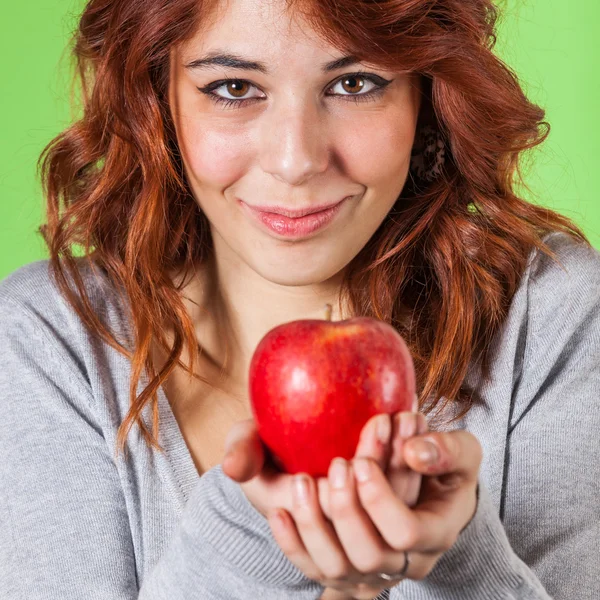 Menina adolescente segurando uma maçã vermelha em fundo verde — Fotografia de Stock