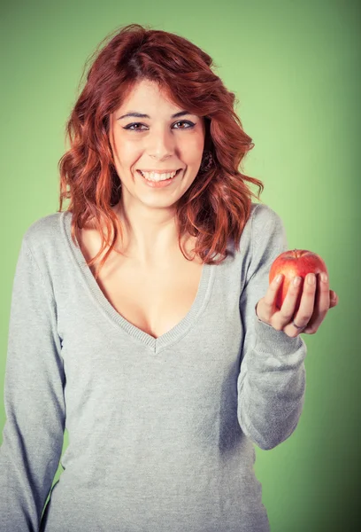 緑の背景に赤いリンゴを保持している 10 代の少女 — ストック写真