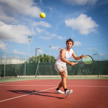 Genç adam tenis oynuyor.