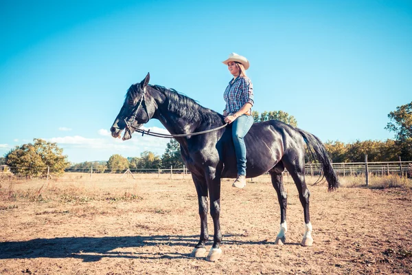 Cowgirl chevauchant un cheval d'étalon noir — Photo