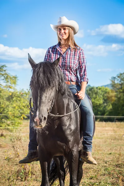 Cowgirl cavalcare un cavallo stallone nero — Foto Stock