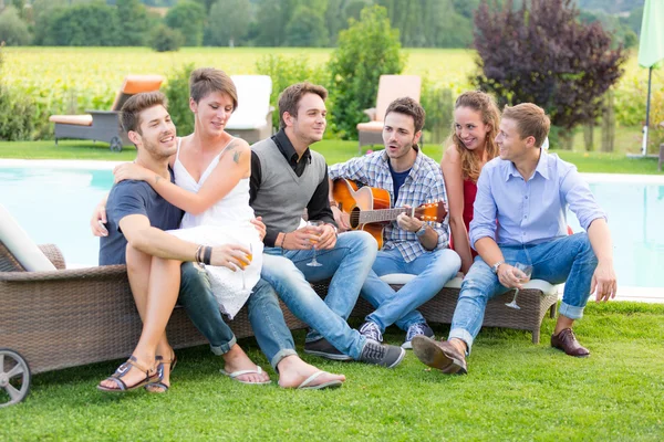 Gruppo di amici che cantano insieme accanto alla piscina — Foto Stock