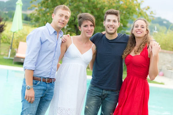 Amigos felices abrazados junto a la piscina — Foto de Stock