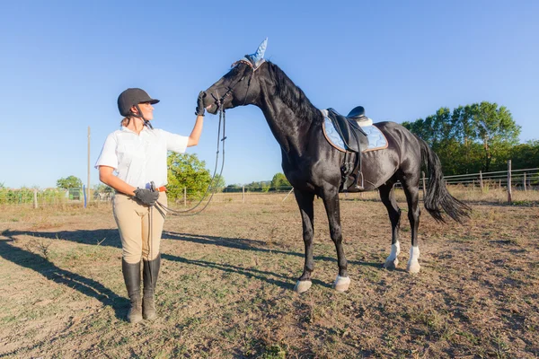 Giovane donna con un cavallo nero — Foto Stock