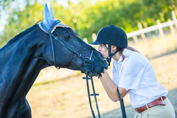 Giovane donna con un cavallo nero — Foto Stock