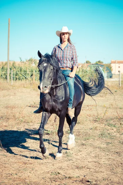 Cowgirl jízdy na koni černý hřebec — Stock fotografie