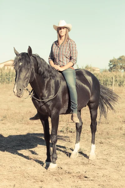 Cowgirl chevauchant un cheval d'étalon noir — Photo