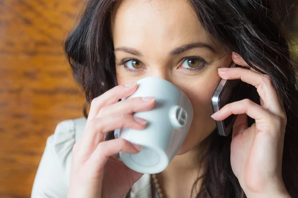 Jonge vrouw op mobiele telefoon in café — Stockfoto