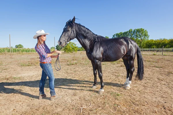 Cowgirl s koněm černý hřebec — Stock fotografie