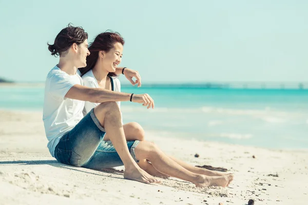 Giovane coppia seduta in una spiaggia caraibica — Foto Stock