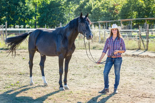 Cowgirl s koněm černý hřebec — Stock fotografie