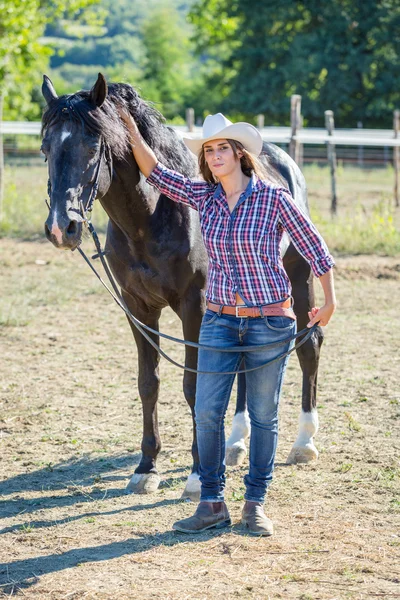 Cowgirl s koněm černý hřebec — Stock fotografie