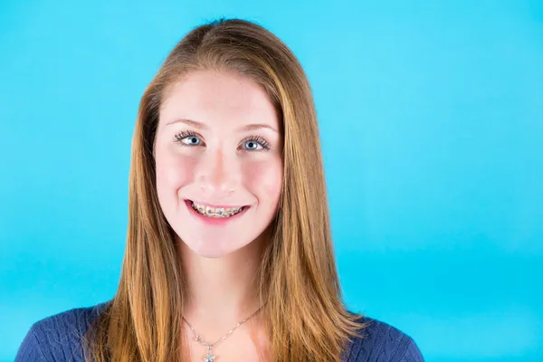 Glimlachend mooi meisje met accolades op blauwe achtergrond — Stockfoto