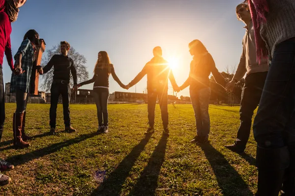 Junge multiethnische Menschen halten Händchen im Kreis Stockbild