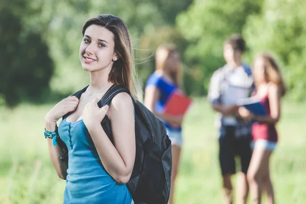 Ung kvinnlig student vid park med vänner — Stockfoto