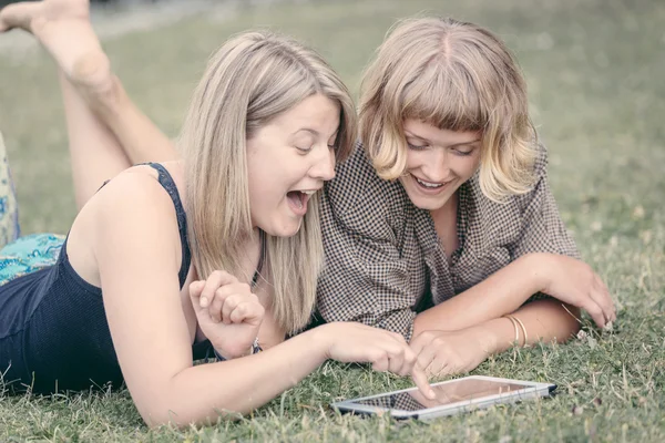 Две русские девушки используют цифровые планшеты в парке — стоковое фото