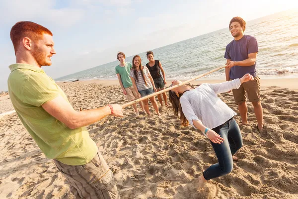 Vrienden limbo te dansen op het strand — Stockfoto