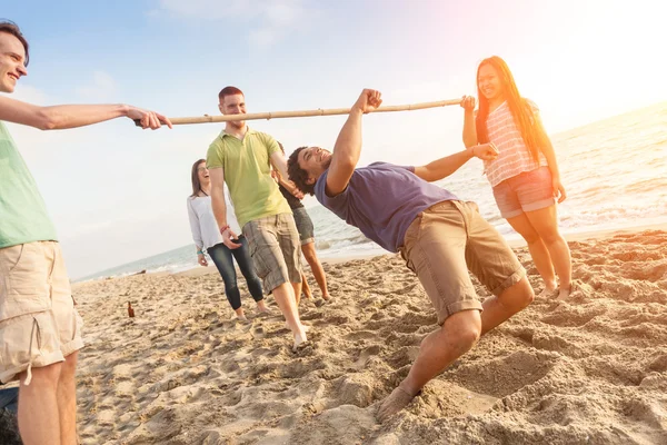 Vrienden limbo te dansen op het strand — Stockfoto