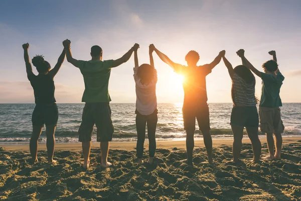 Les gens avec les bras levés regardant le coucher du soleil — Photo