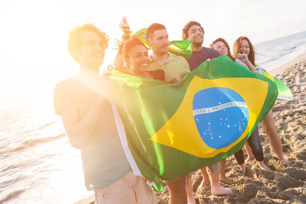 Přátelé s brazilská vlajka na pláži — Stock fotografie