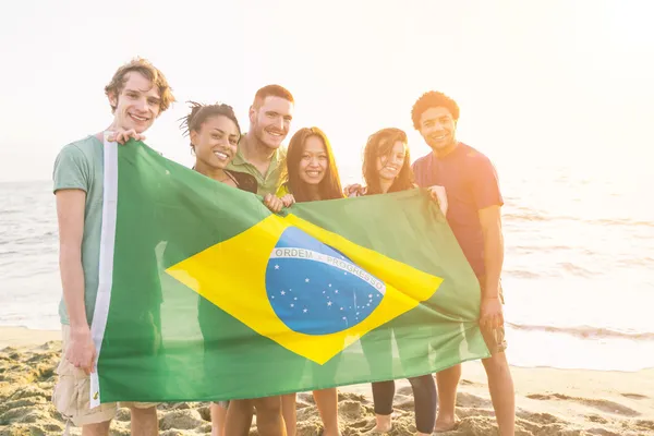 Přátelé s brazilská vlajka na pláži — Stock fotografie