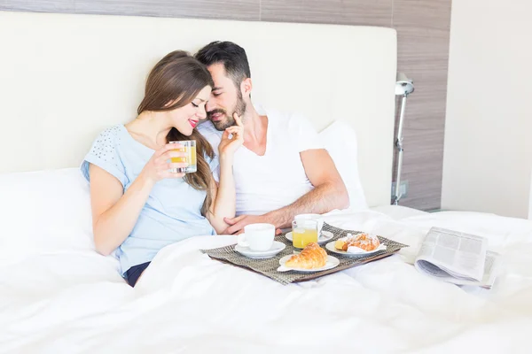 ホテルのベッドルームで朝食を持っているカップル — ストック写真