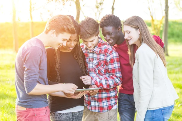 Teenage vrienden met behulp van digitale tablet in het park — Stockfoto