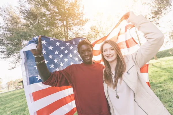 Casal Multiracial segurando bandeira americana — Fotografia de Stock