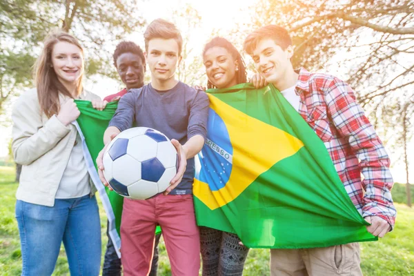 Amigos adolescentes sosteniendo bandera brasileña y balón de fútbol — Foto de Stock