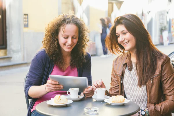 Meninas usando tablet digital ao tomar café da manhã — Fotografia de Stock