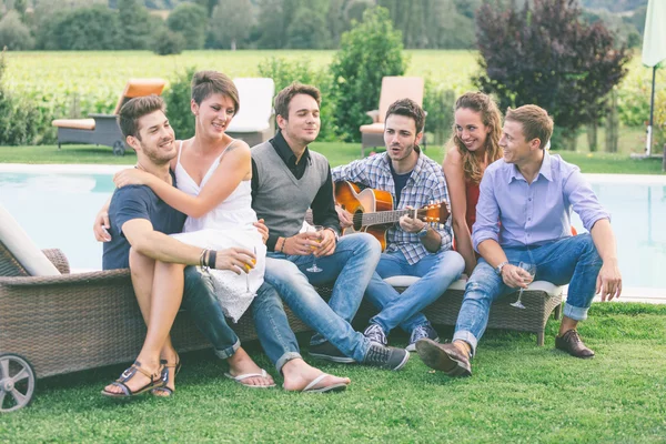 Grupo de amigos cantando juntos junto a la piscina — Foto de Stock