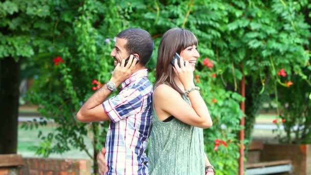 Молодой человек и женщина разговаривают по мобильному телефону — стоковое видео