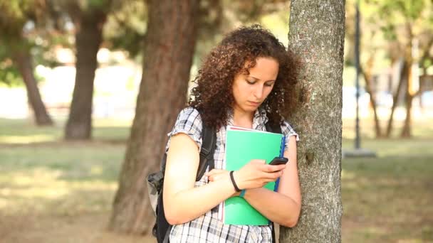 Student met mobiele telefoon in het park — Stockvideo