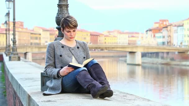 Chica leyendo un libro a lo largo del río — Vídeo de stock