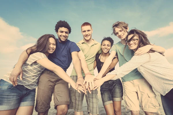 Çok ırklı bir grup arkadaşıyla birlikte yığın üzerinde el ile — Stok fotoğraf