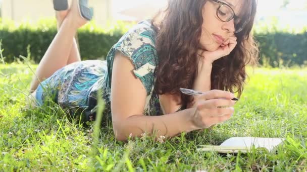 Mujer escribiendo en su diario en el césped — Vídeos de Stock