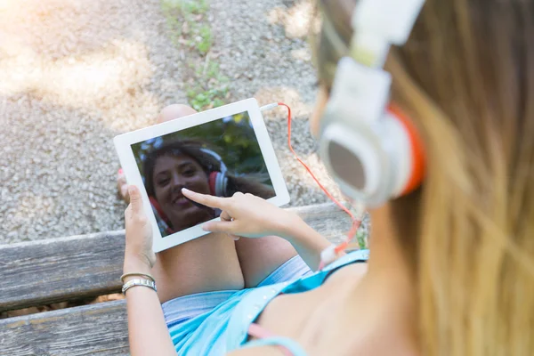 Piękna młoda kobieta z cyfrowego tabletu w parku — Zdjęcie stockowe