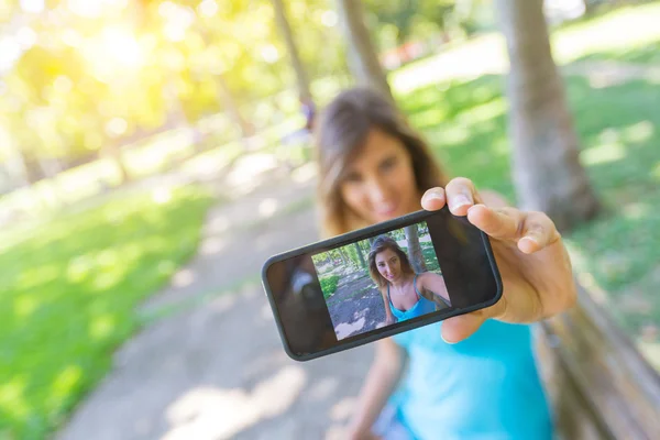 Bela jovem mulher tomando selfie no parque — Fotografia de Stock